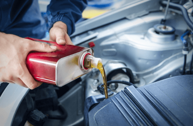 An A Plus Auto mechanic adding car oil to a vehicle