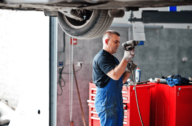 A member of the A Plus Auto team performs regular car repairs at work.